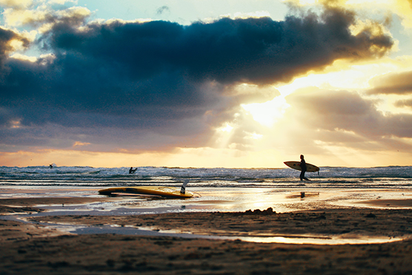 Fistral Beach in the summer with a surfer walking to the water. 