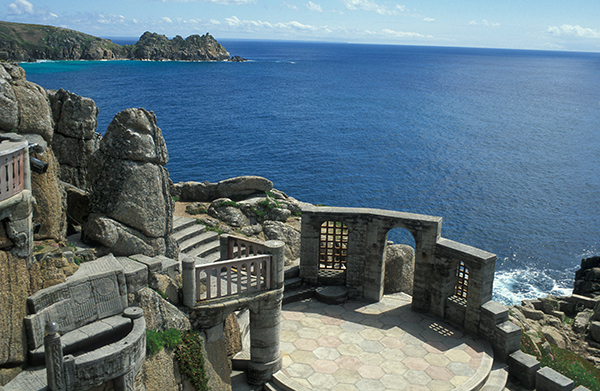 The Minack open air theatre in Cornwall, with the sea in the background and a clear blue sky.